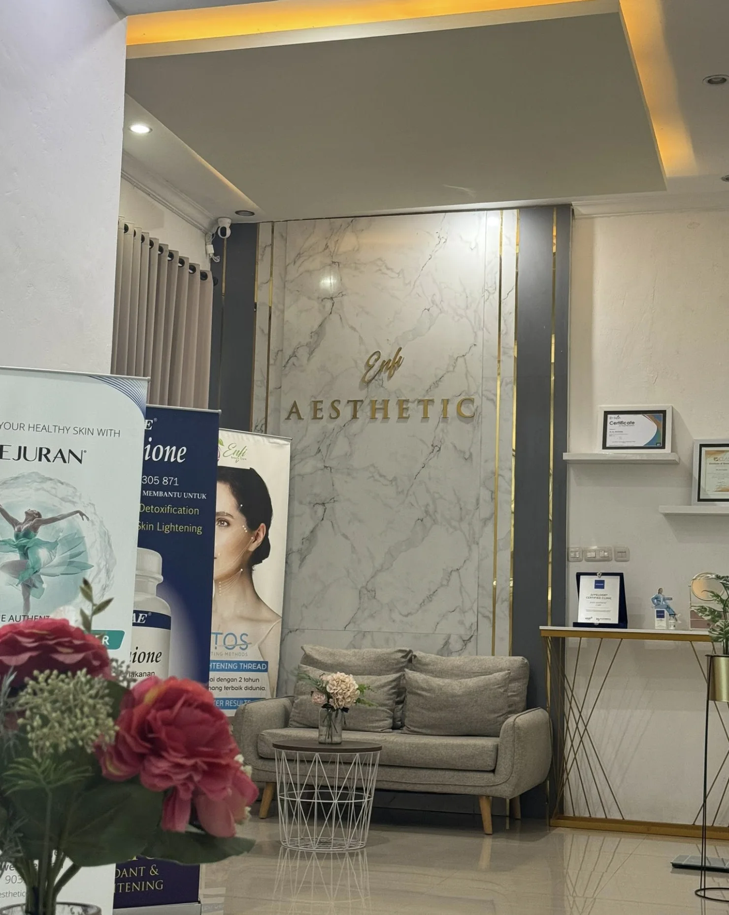 Ruang tunggu ENFI Aesthetic Clinic Bone dengan dinding marmer berlogo Enfi Aesthetic