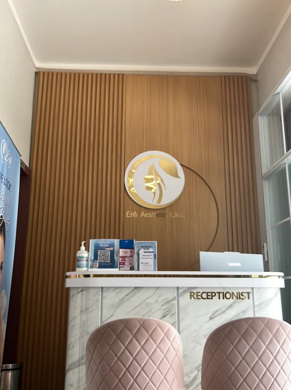 Meja resepsionis ENFI Aesthetic Clinic Makassar dengan logo klinik